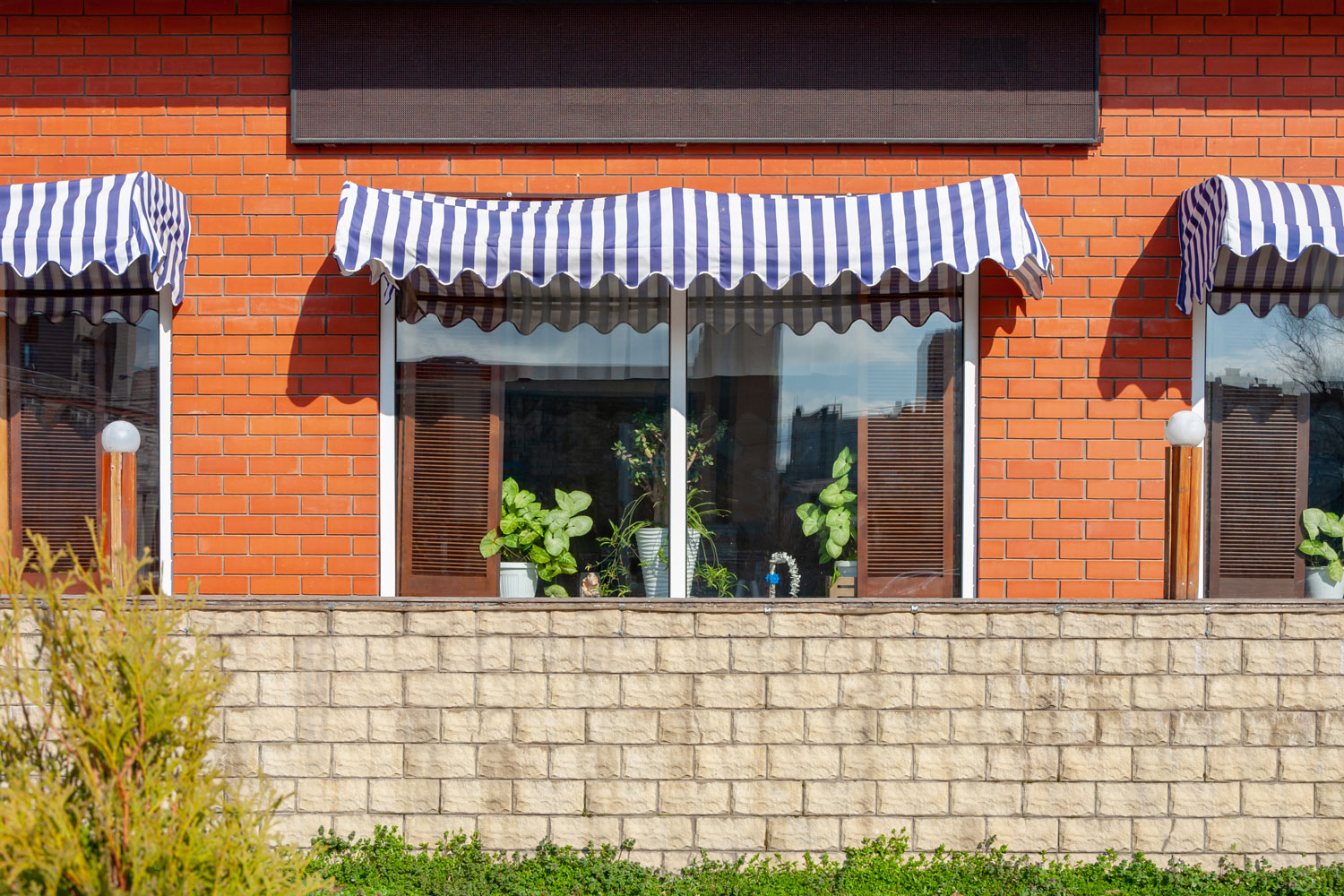 A seamless clear window with white trims and an awning at a brick restaurant