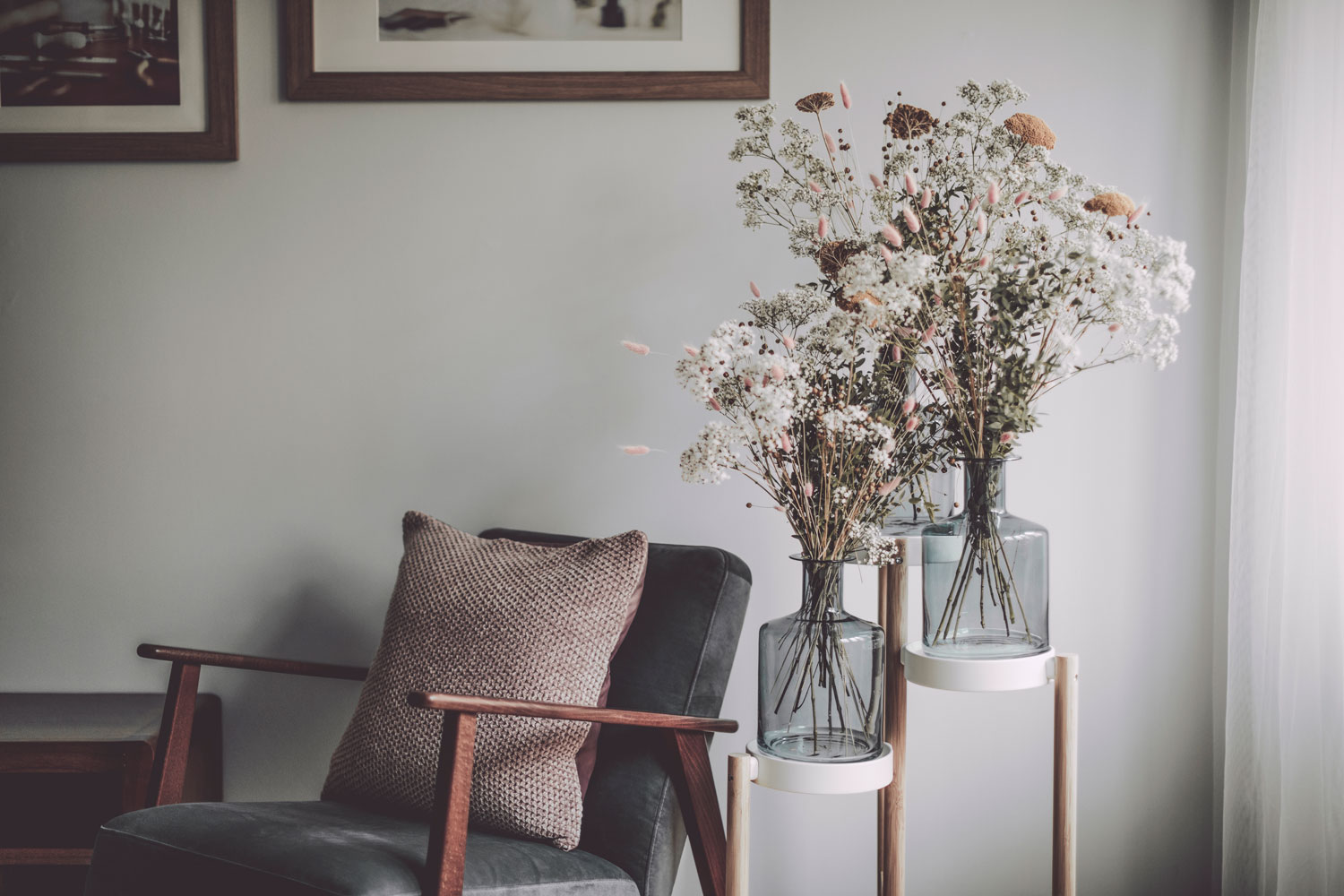 A small wooden chair with gray foam and a pillow next to flowers