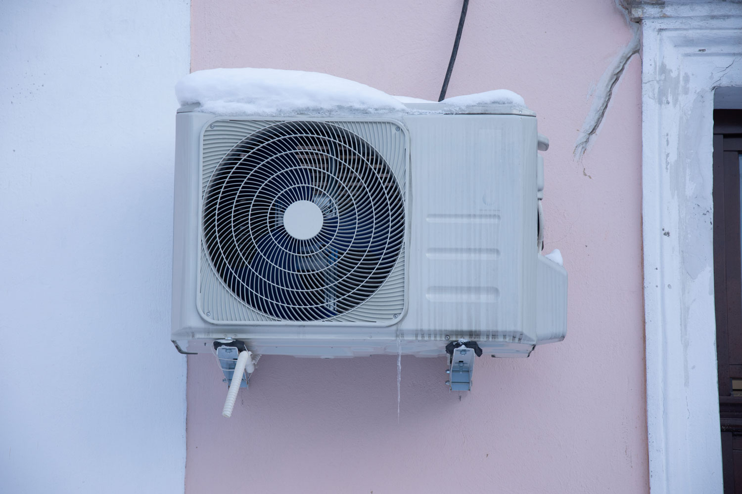 An air conditioning unit mounted on the wall outside of a house