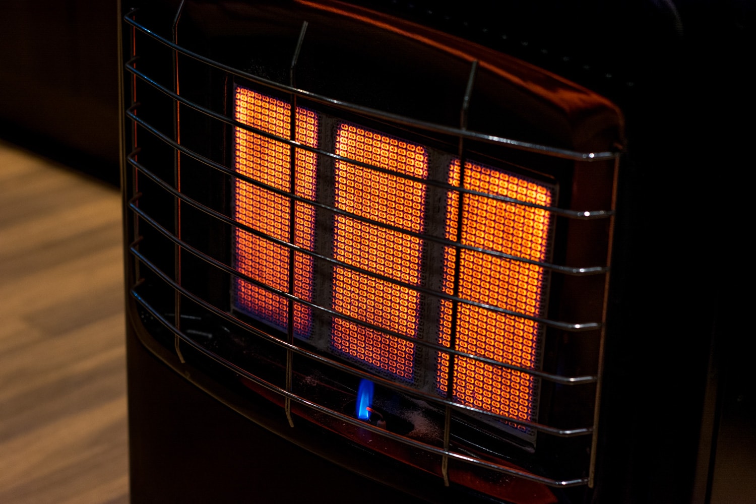 An isolated gas heater on a freezing cold winter night burning at full capacity, glowing orange and radiating heat.
