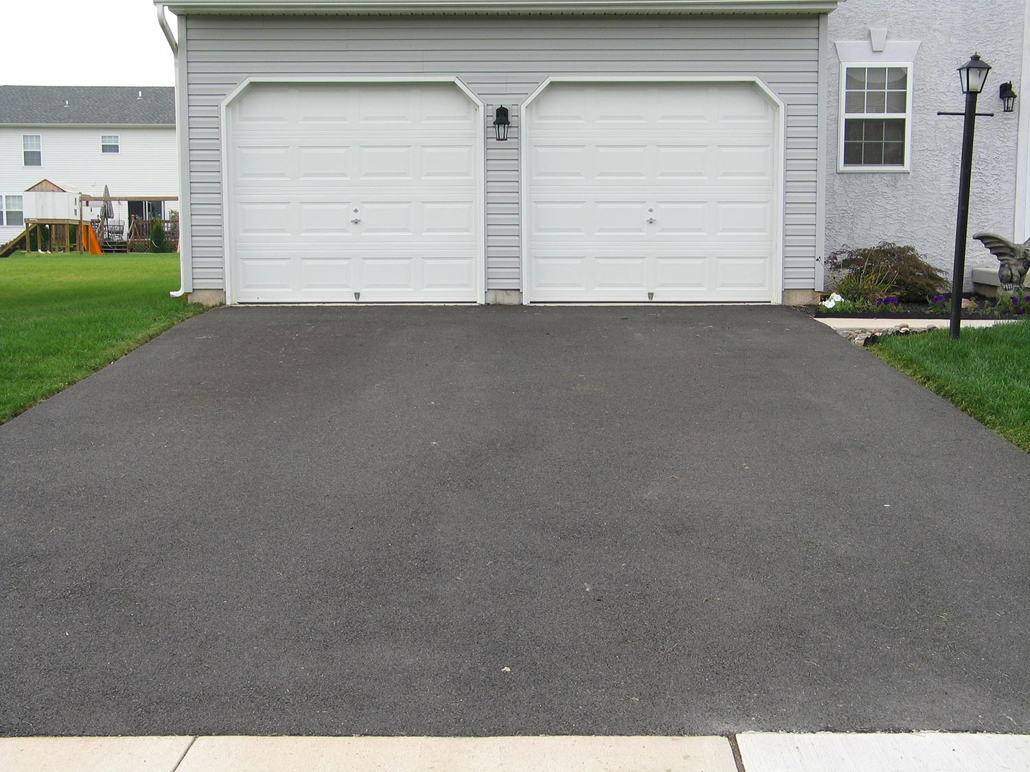 Double garage with white doors at the end of a driveway