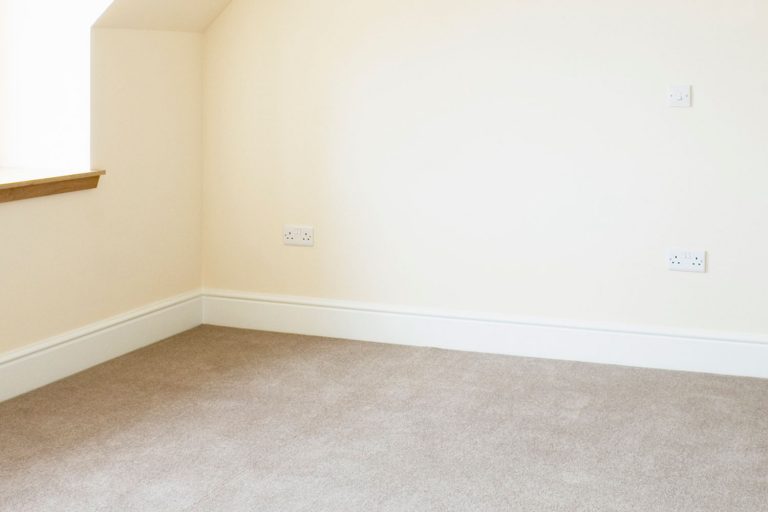 Empty interior of bedroom in a newly built house with baseboard and carpet, How To Seal Gap Between The Carpet And Wall