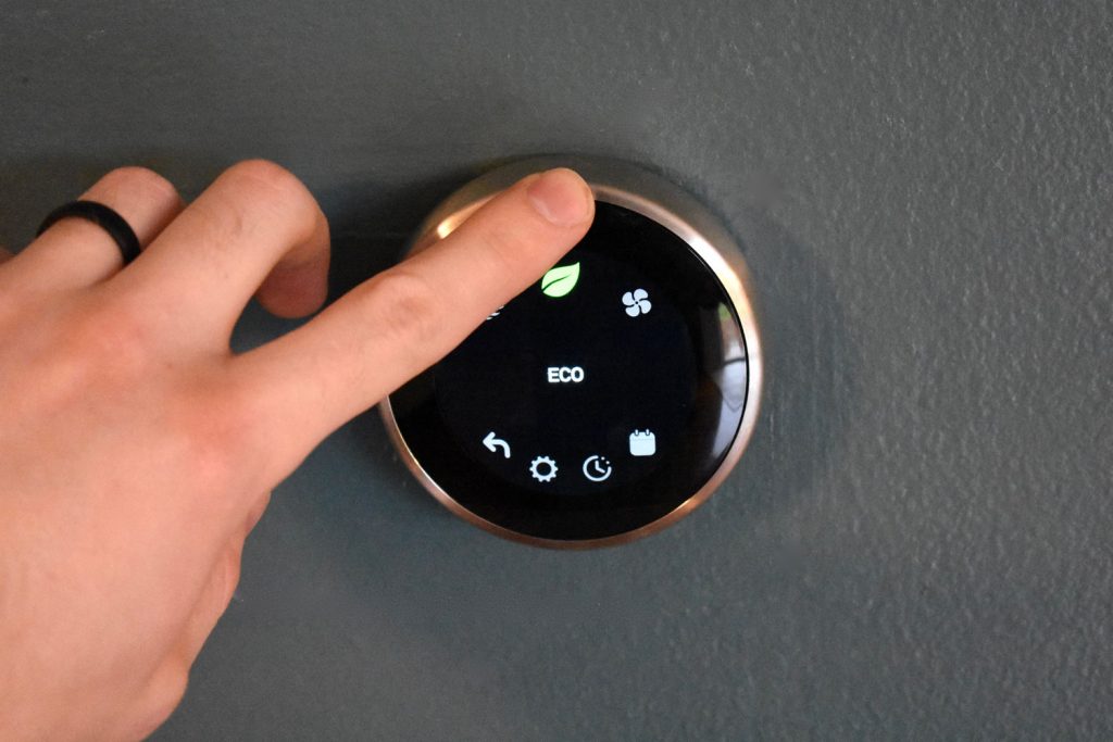 Finger using touchscreen to save money with electric thermostat