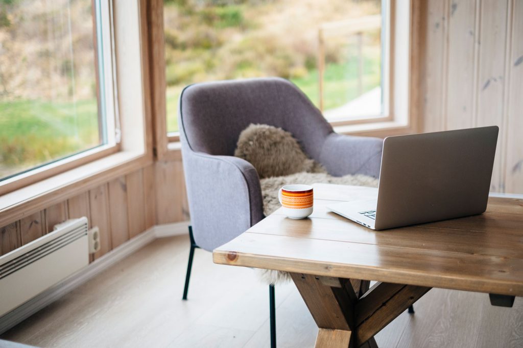 Home office in cozy living room. A comfortable chair, with a laptop and a coffee cup on a table in front