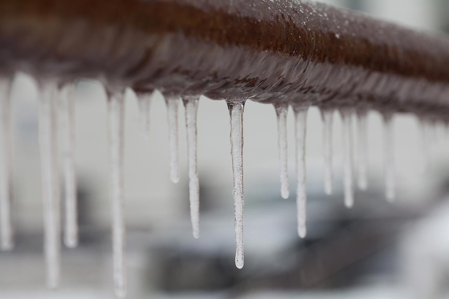 Icicles hanging from a brown pipe