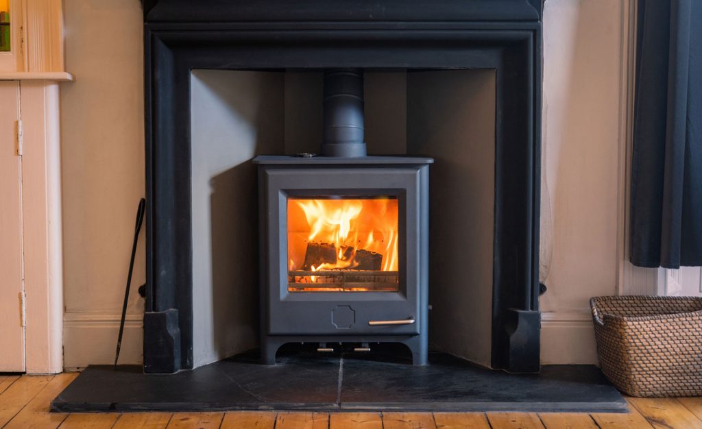 Logs burning in a modern wood burning stove with a large glass viewing screen.