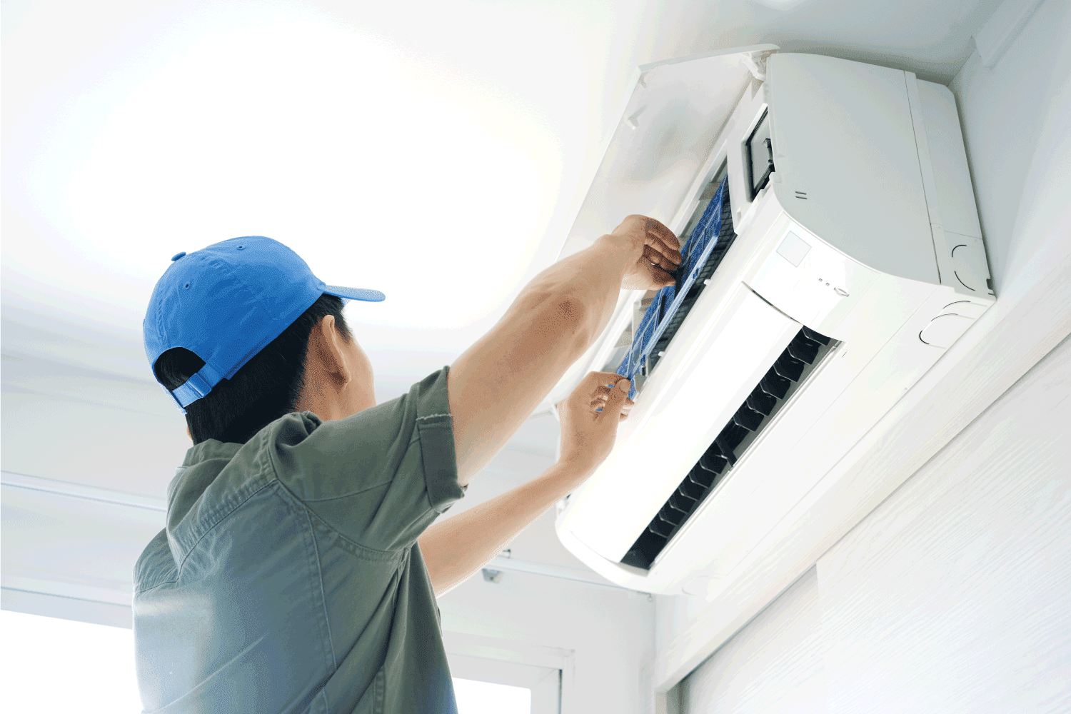 Male repairing air conditioner inside room