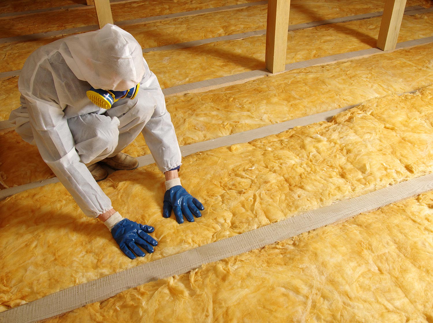 Man installing thermal roof insulation layer using mineral wool