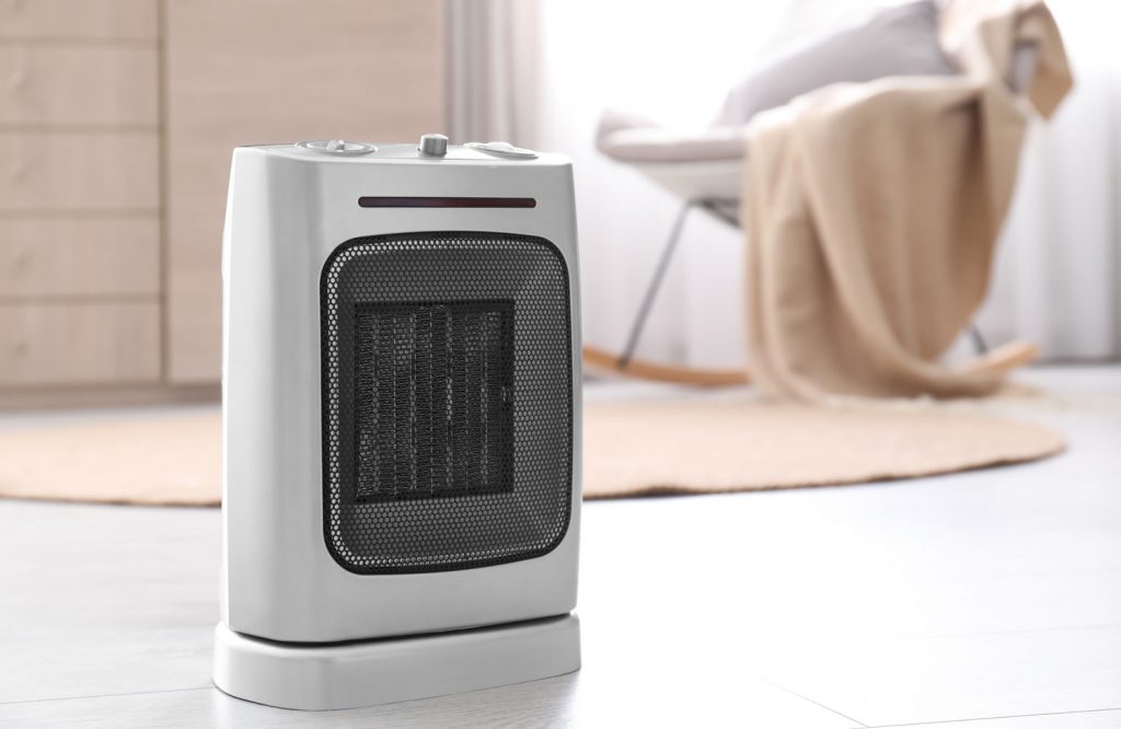 Modern electric fan heater on floor in room.