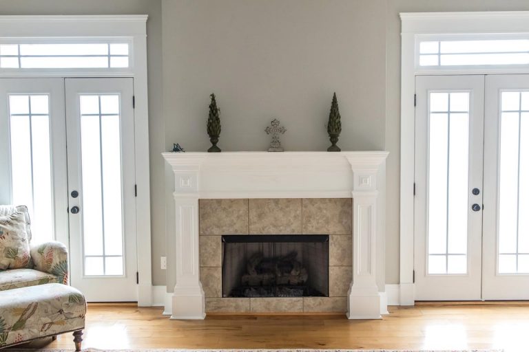 A neutral beige gray living room den in a new construction house with a white and tiled fireplace, Can You Knock Down a Wall with a Fireplace?