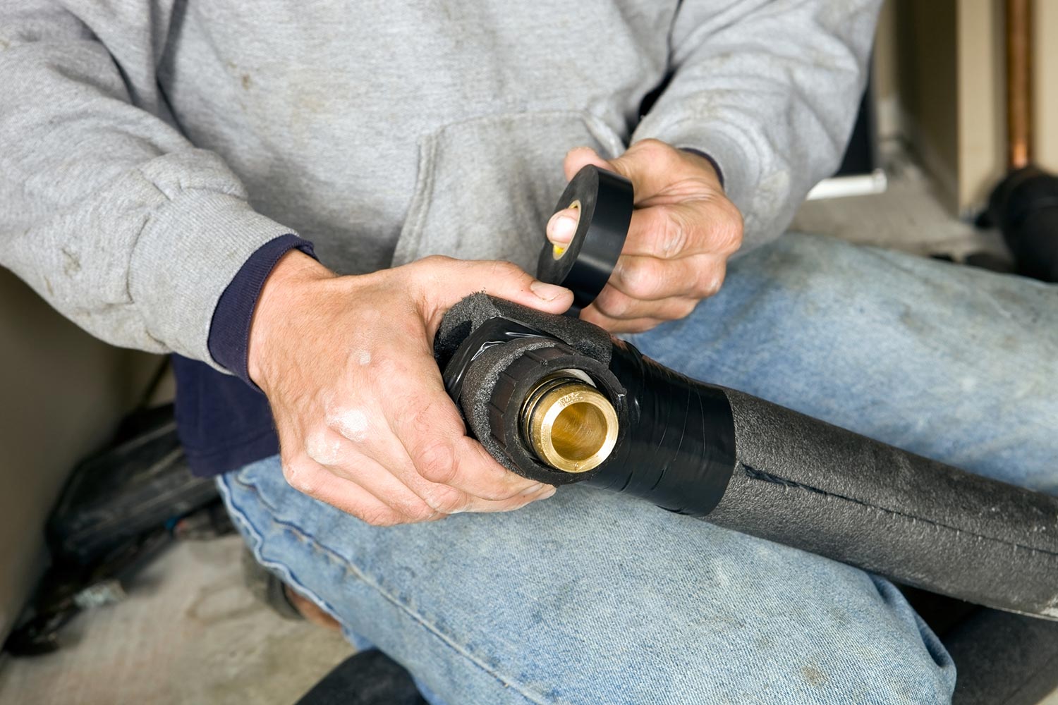 Plumber fastening pipe insulation with electrical tape