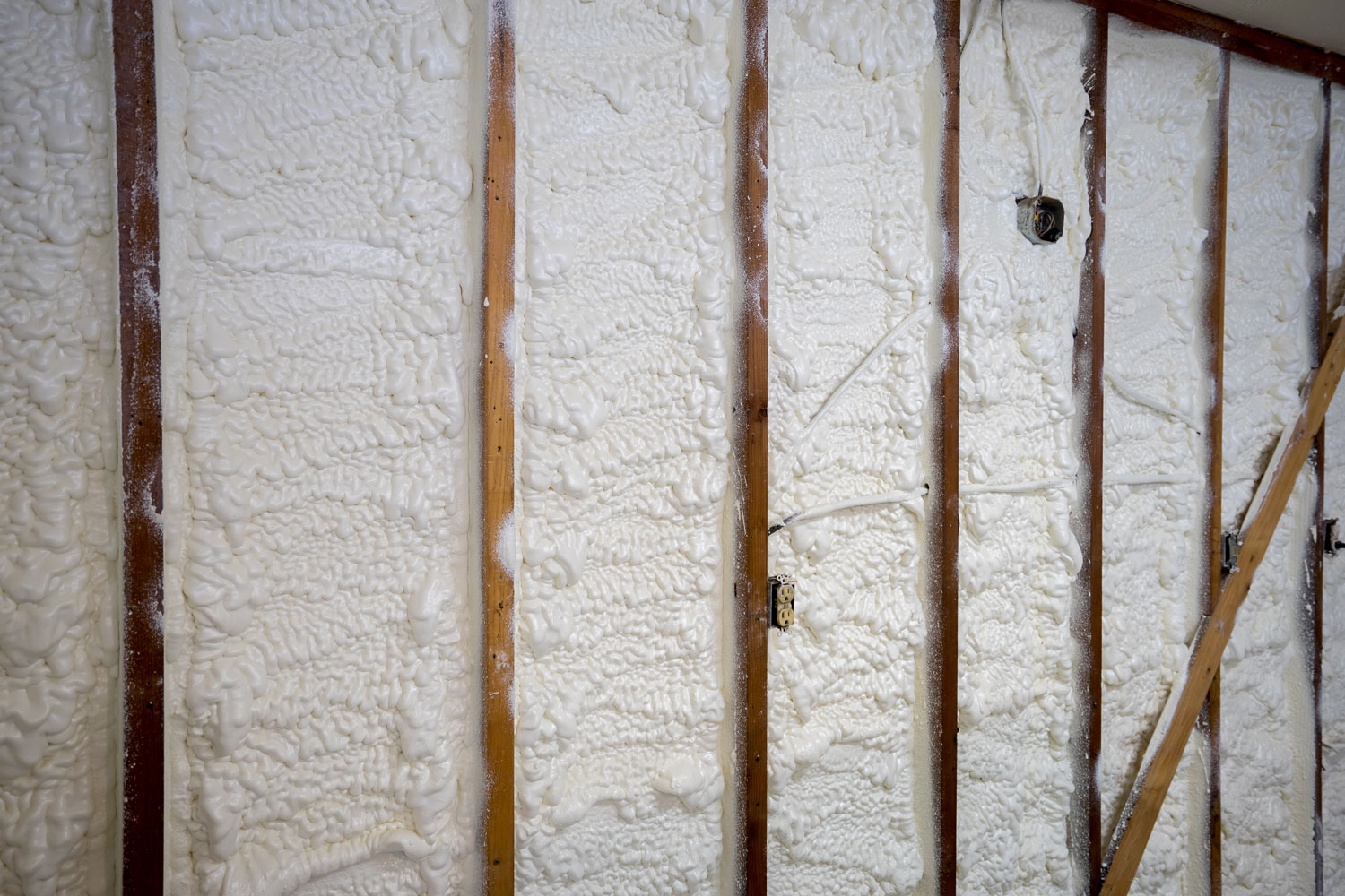Spray foam insulation between the wooden framing of the house