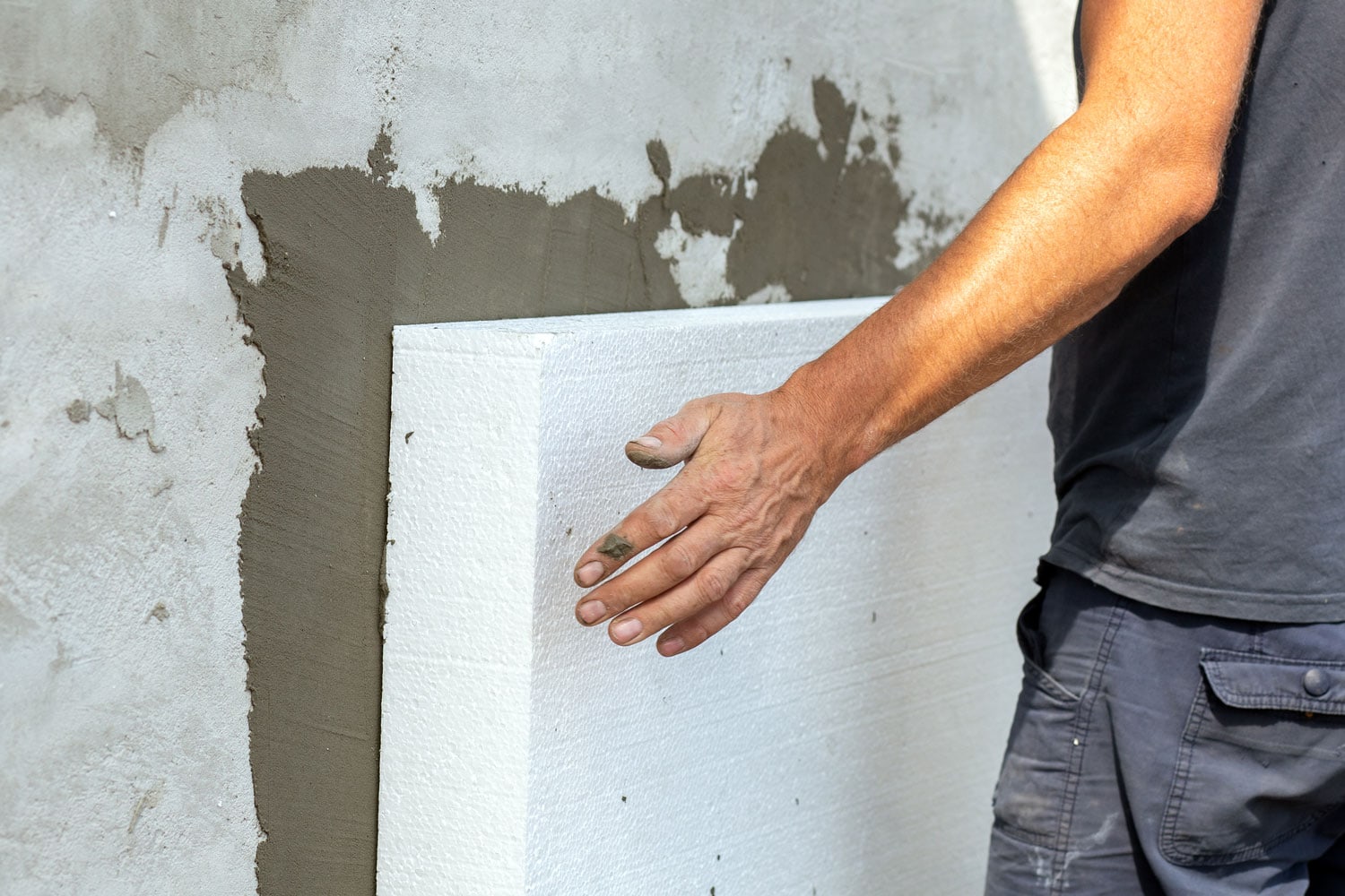 Technician installing rigid foam insulation on the exterior wall