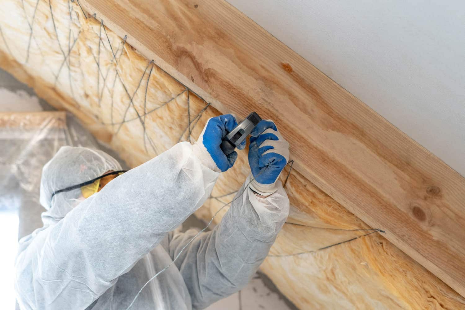 Technician tying in the fiberglass insulation on the wall