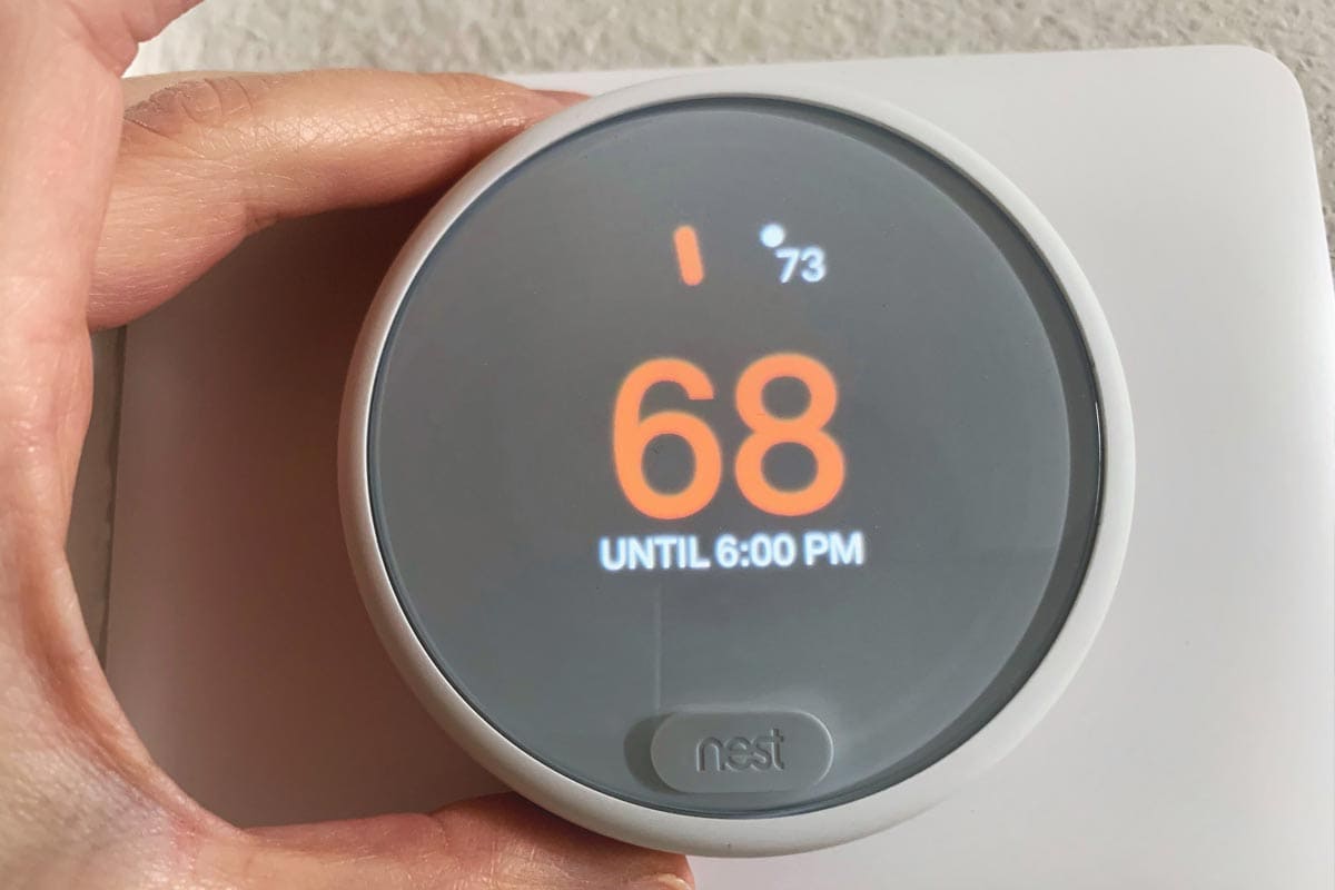 A white nest thermostat used to save energy and cut costs on your electric bill