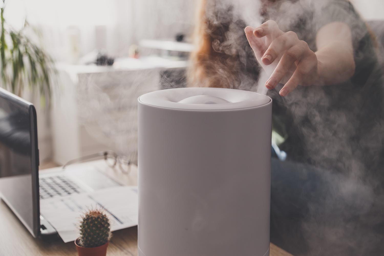 Woman freelancer uses a household humidifier in the workplace at home office