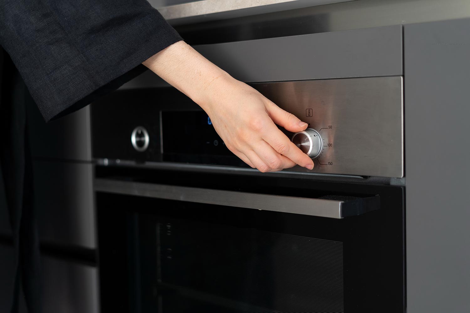 Woman hand turning off an oven to lower temperature in the house