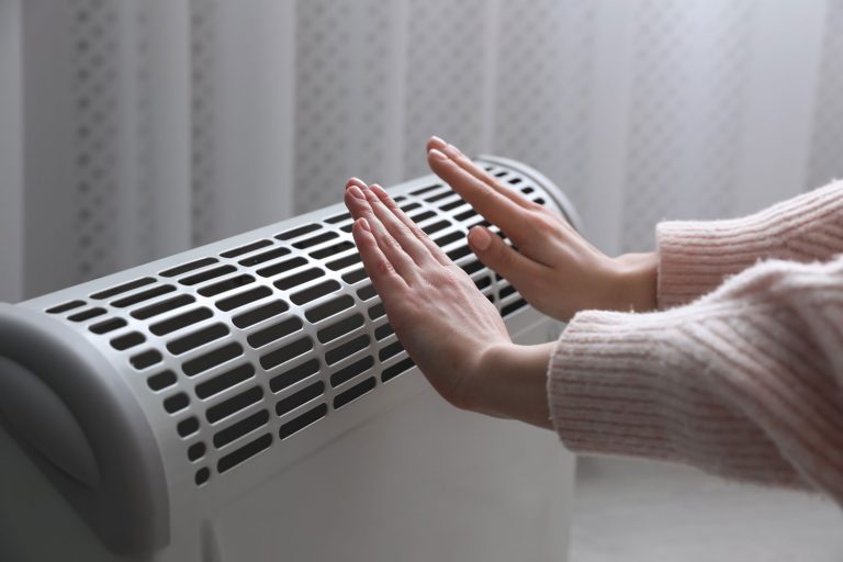 Woman warming hands near gas heater at home, closeup, How To Light An Empire Heater