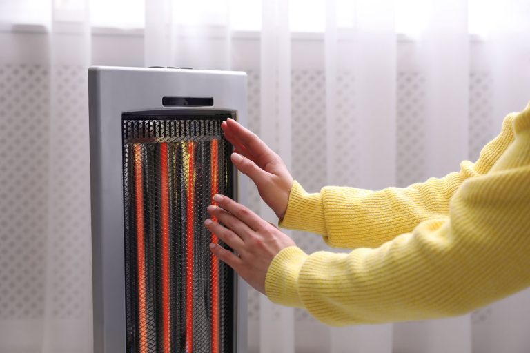 Woman warming hands near heater indoors, 4 Best Heaters For An Office Desk