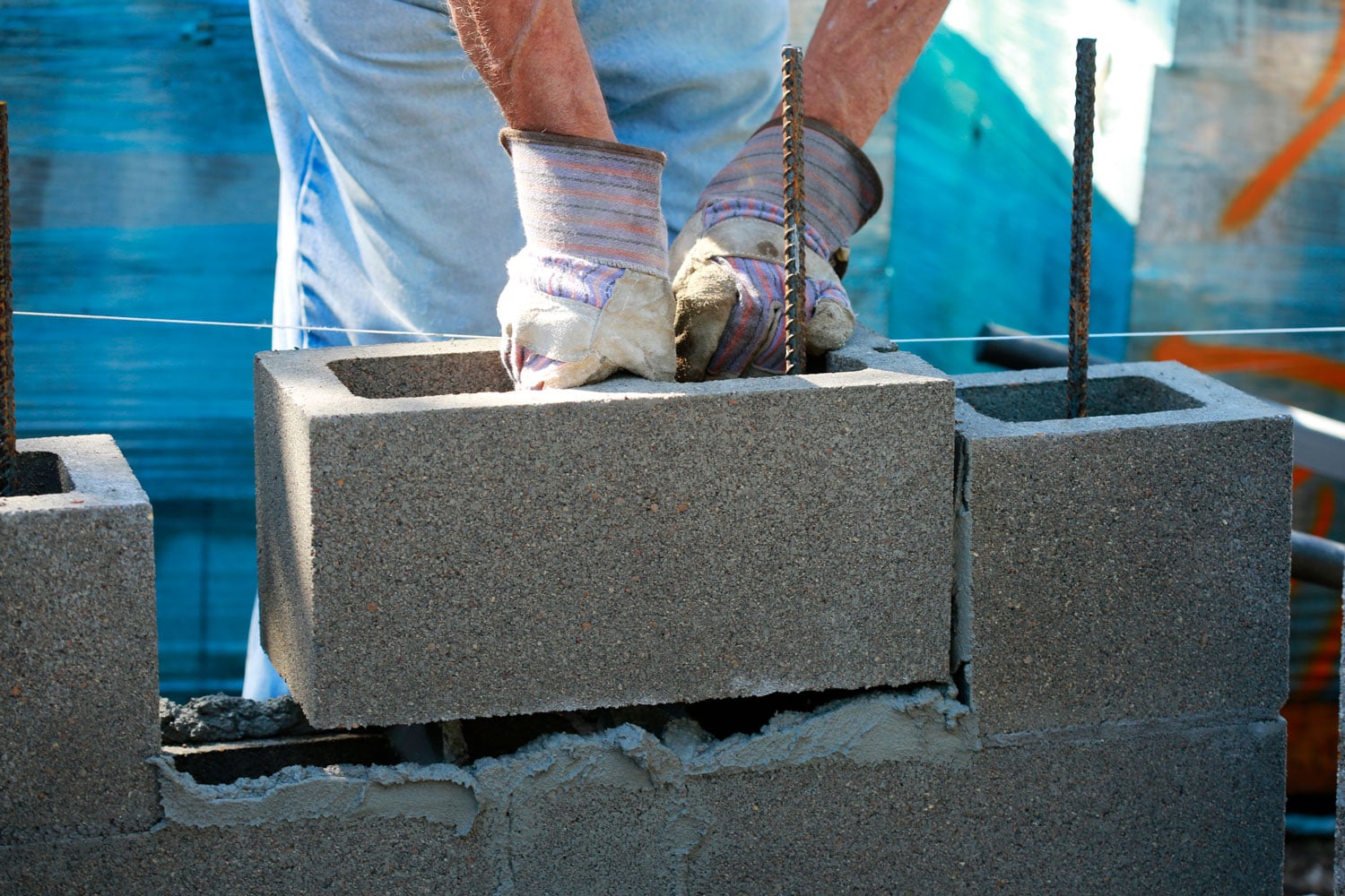 Worker properly laying out concrete blocks for a house under construction