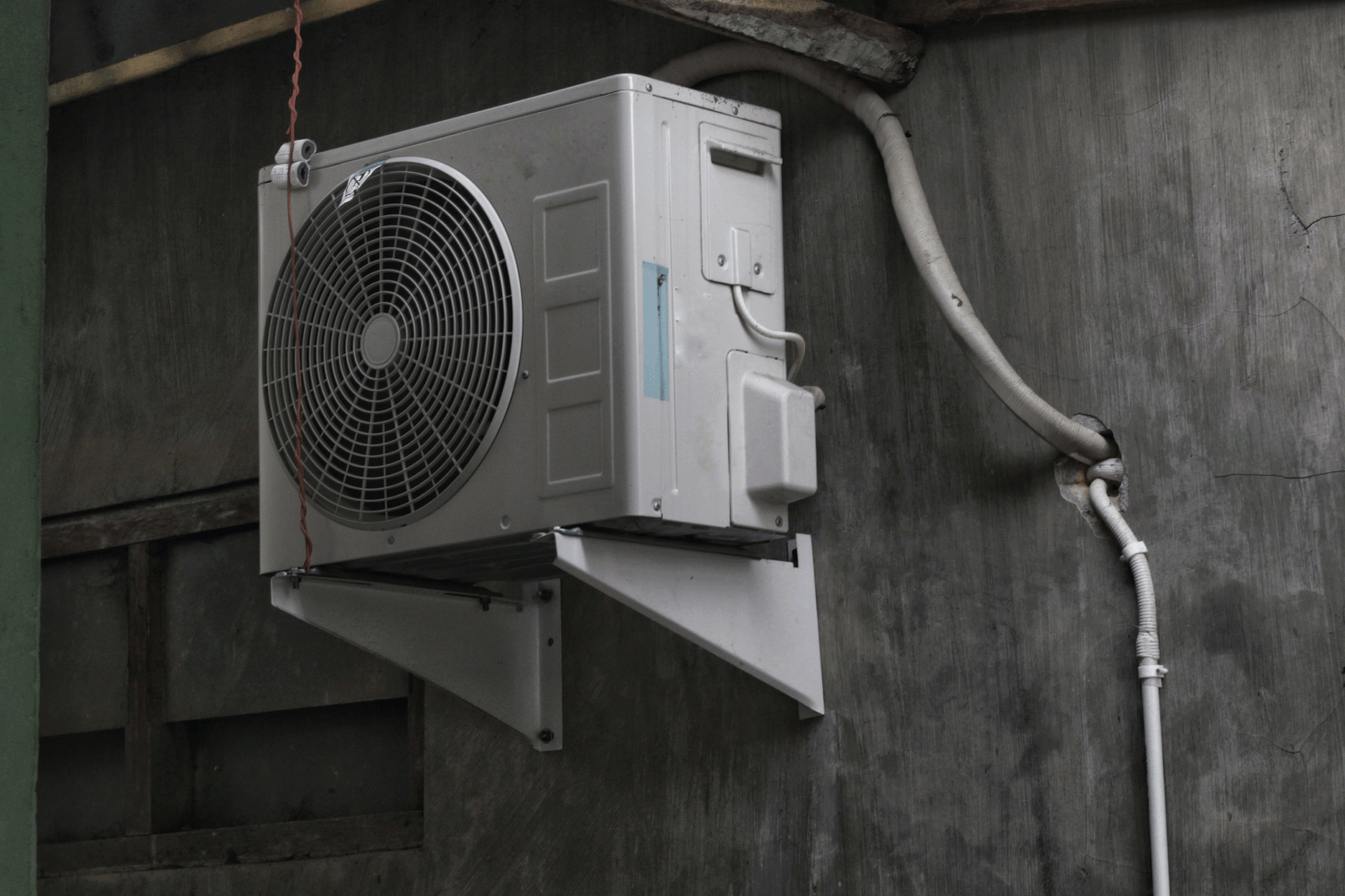 outdoor heat pump sticking out a gray wall