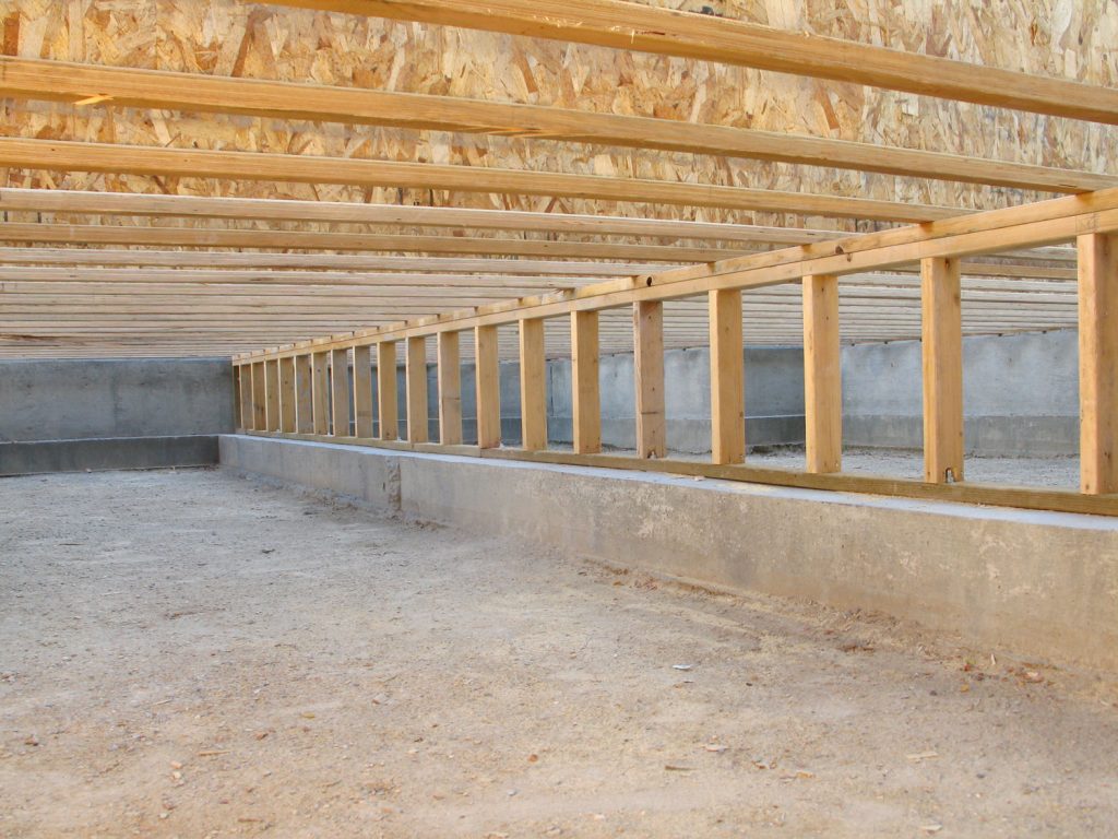  photo shows a view of the crawlspace foundation beneath the framing of a new house