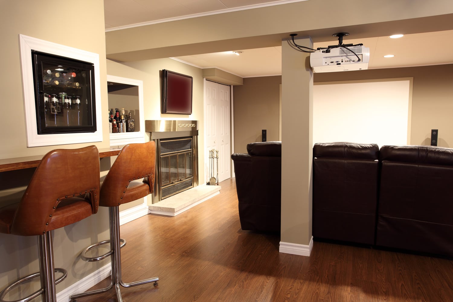 A DSLR photo of a Modern living room located in the basement of a bungalow with a wooden floor, a bar, mimi fridge and fournitures. 