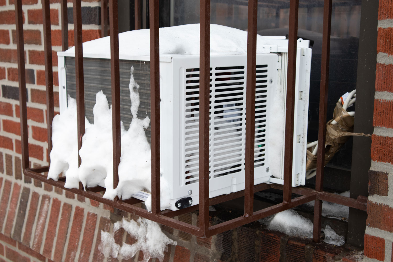 A cage window air conditioning unit at a small apartment building
