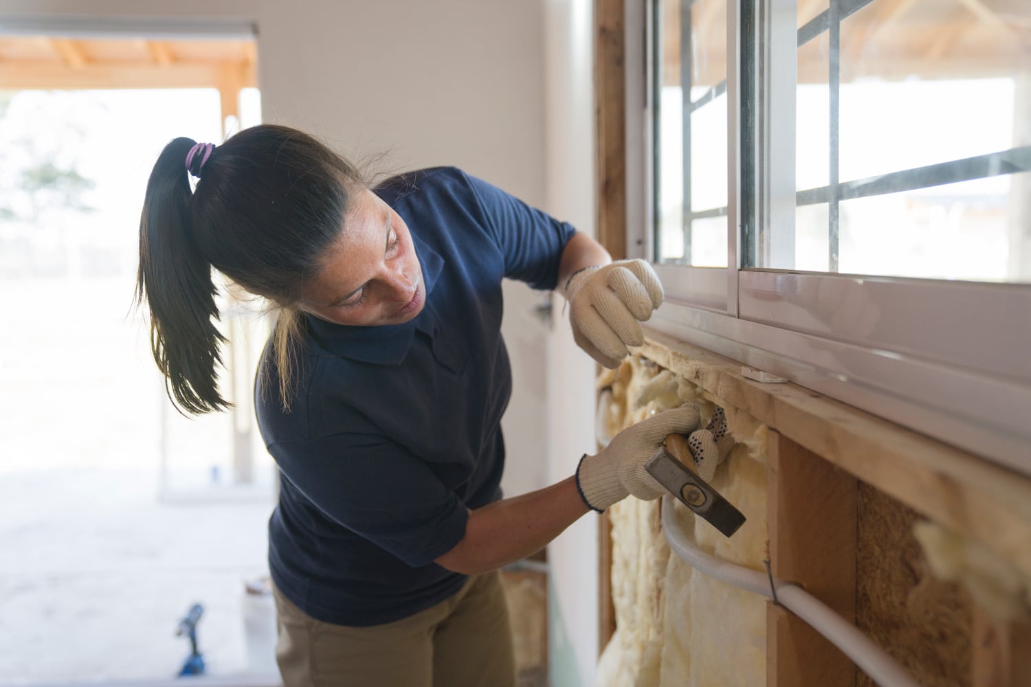 A female worker is installing a fiberglass insulation