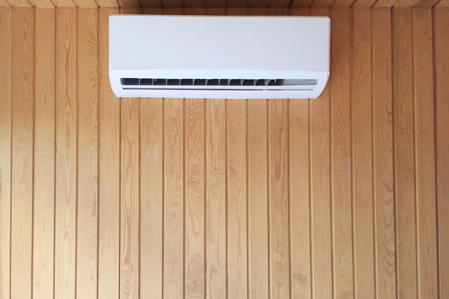 A min split air conditioning unit mounted on the wooden paneling wall