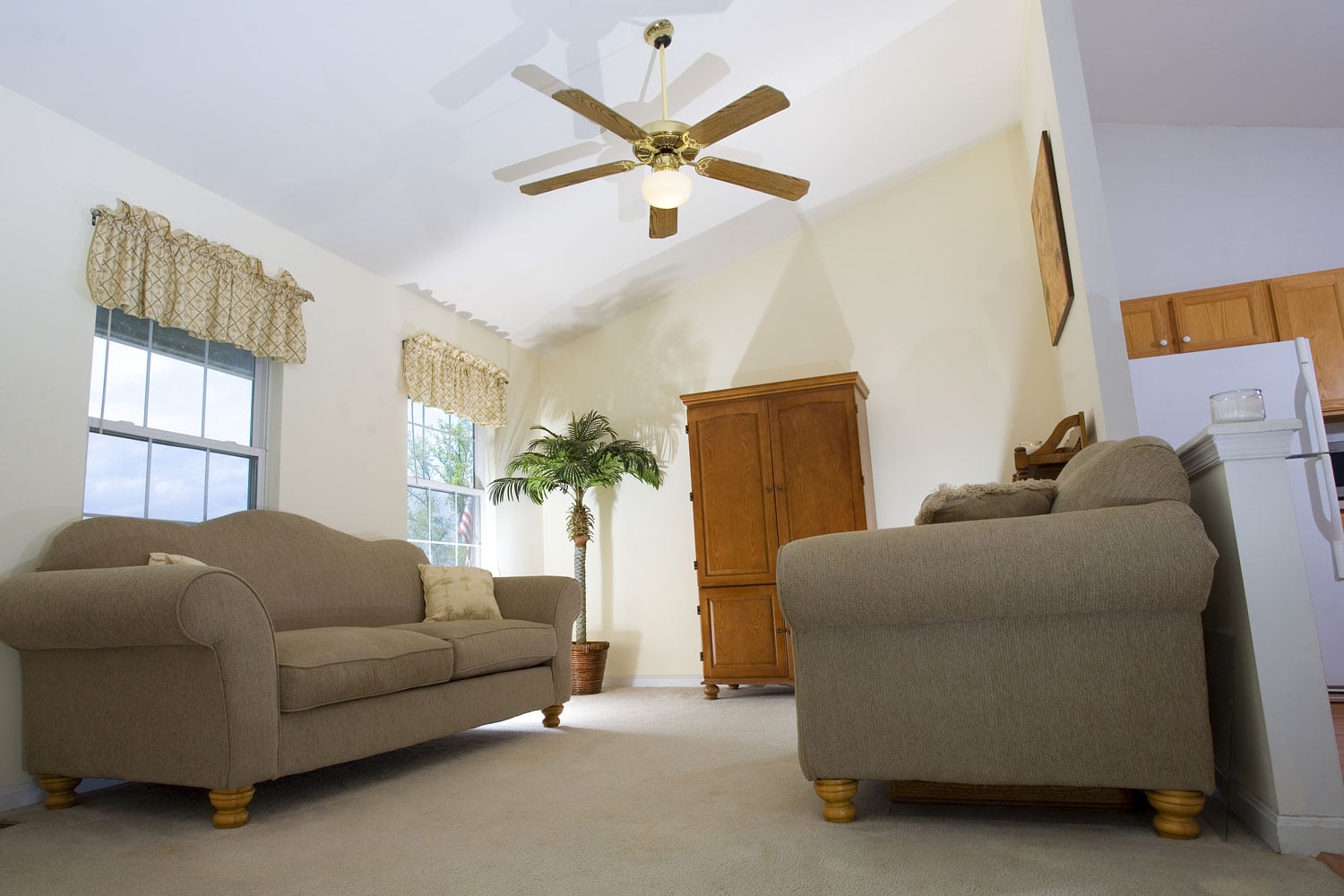 A spacious living room interior with gray sofas, white walls and a ceiling fan