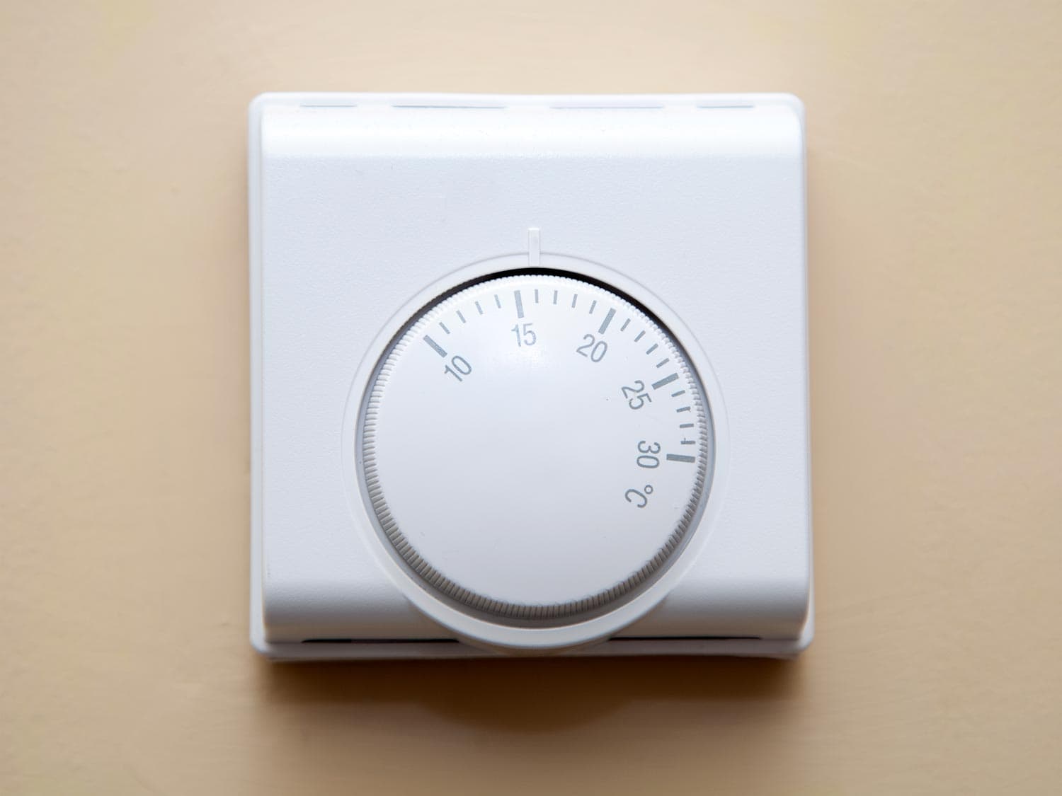 A typical home heating thermostatic control dial on a wall