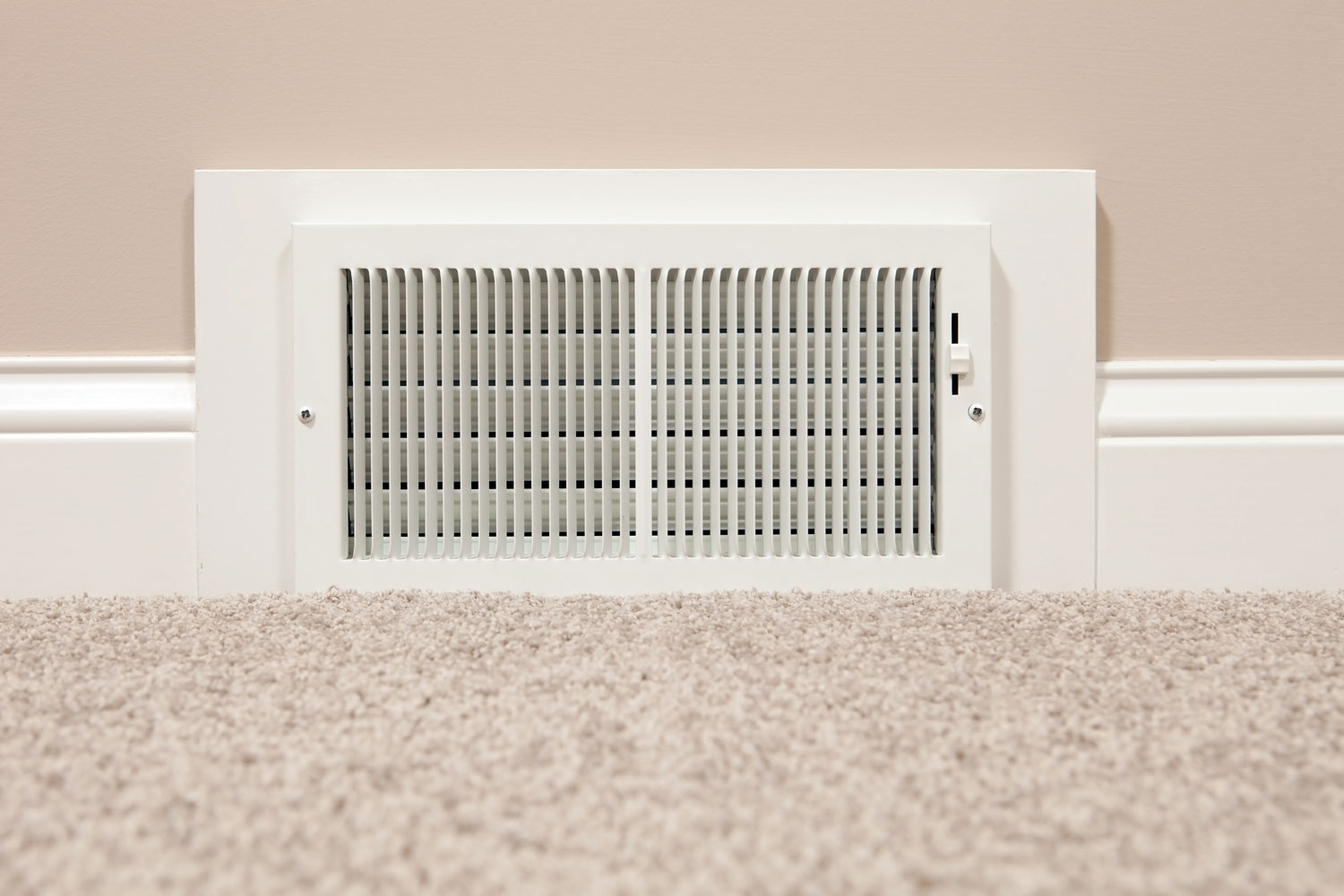 A vent inside a living area with carpeted flooring