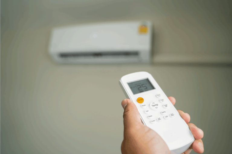 Air-conditioner-inside-top-the-room-man-operating-remote-controller.-Does-Air-Conditioning-Use-Gas-Or-Electricity