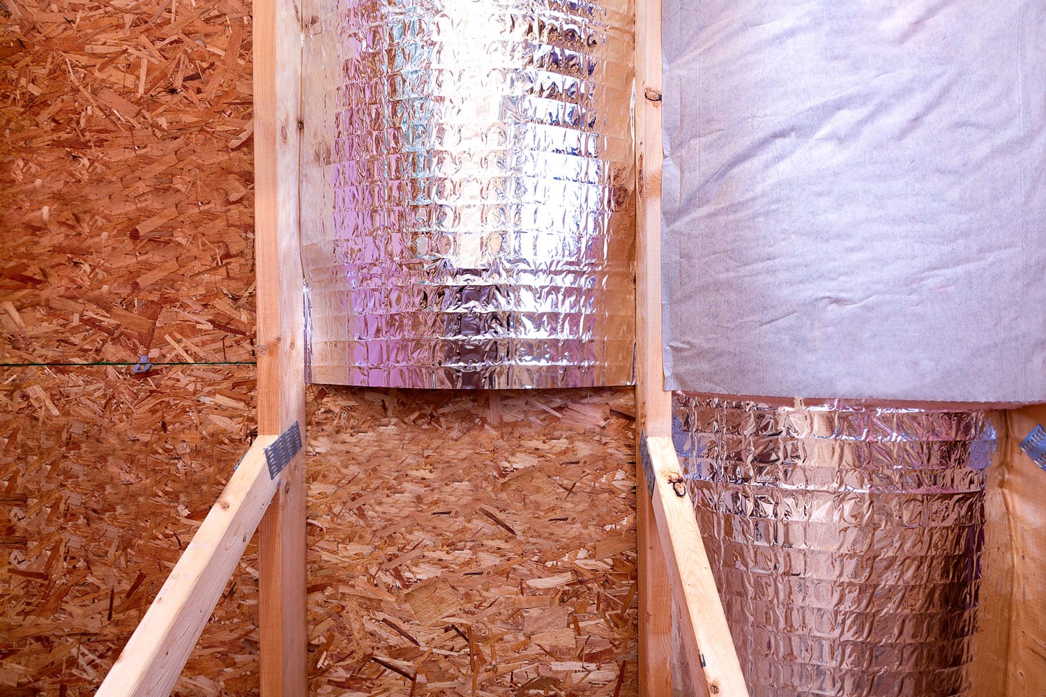 Attic insulating with reflective heat barrier and fiberglass cold barrier between the attic joists