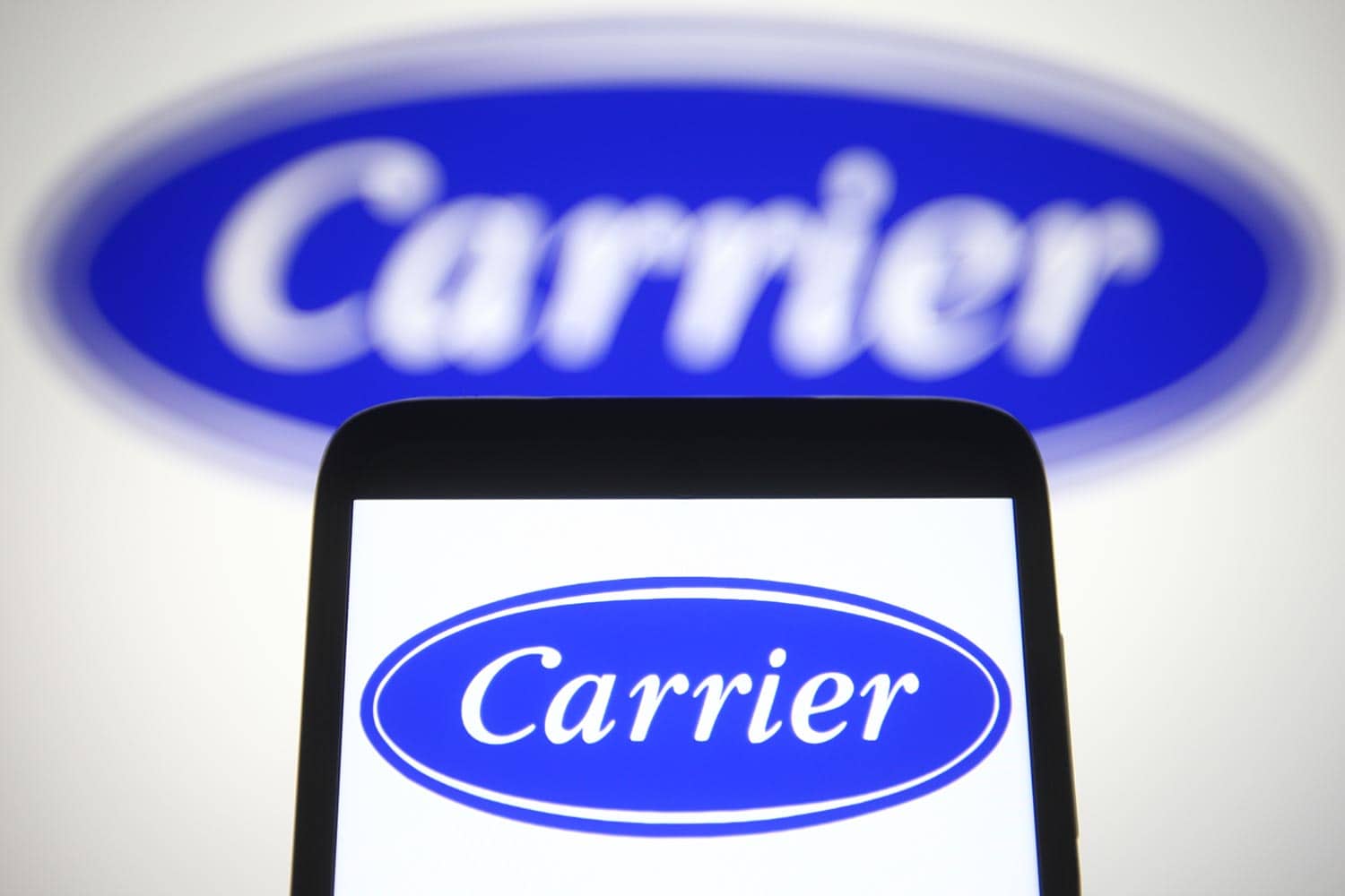 Carrier Global Corporation logo is seen on a mobile phone and a computer screen