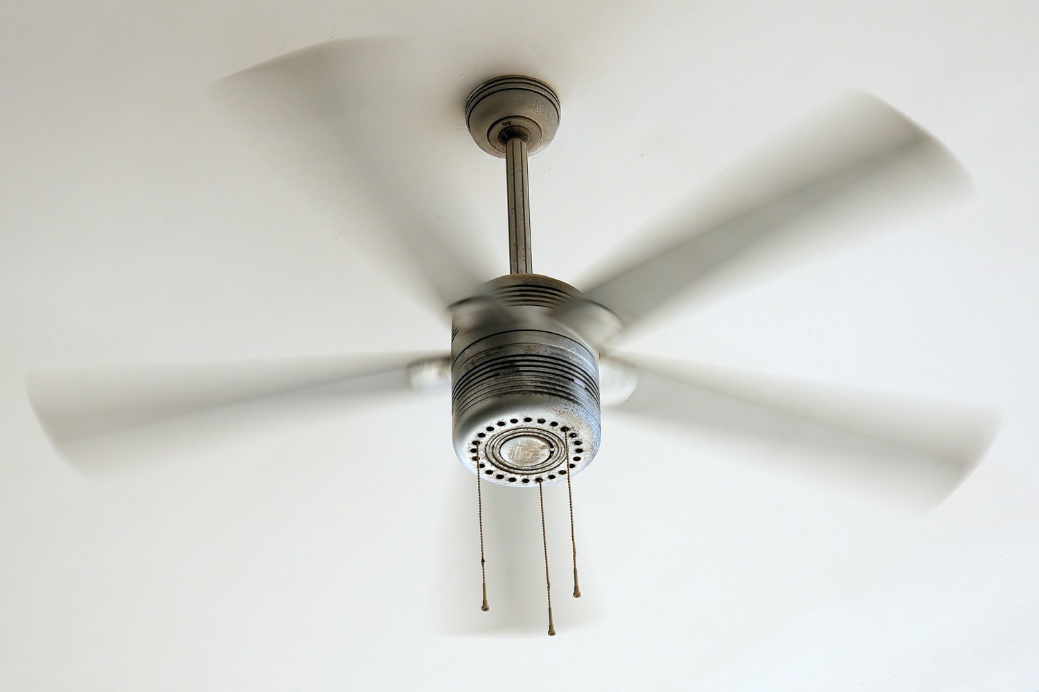 Ceiling fan is rotating at the ceiling of the room. Electric climate equipment.