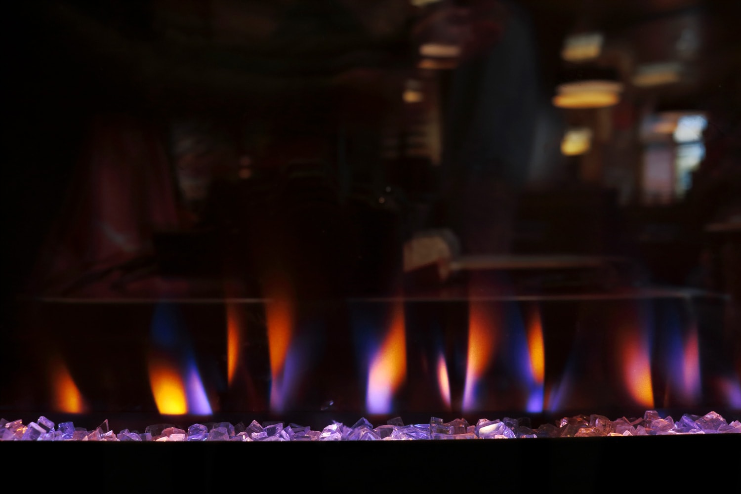 Electric stove as fireplace as a decorative heater in use. Reflection of the interior of a lounge or restaurant on the front panel.