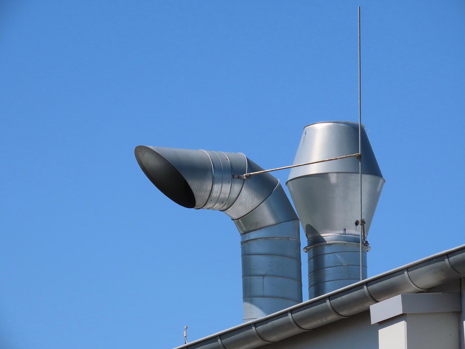 Exhaust chimneys of a ventilation system on top of a roof against bright blue sky