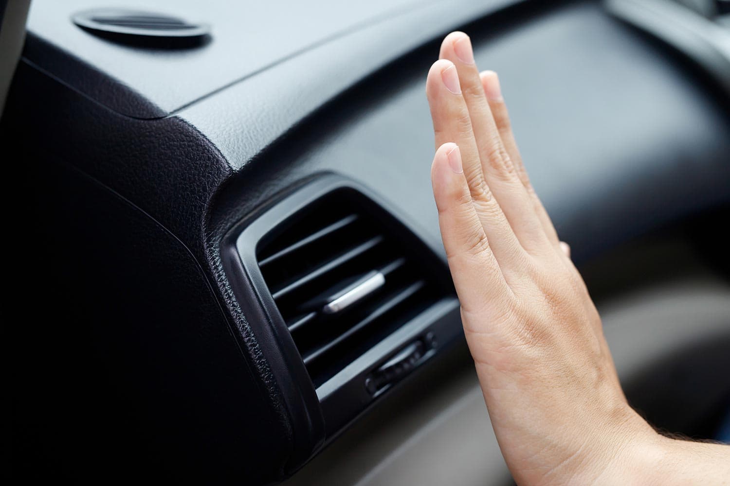 Female hand checking the cooling of the air conditioner in the car