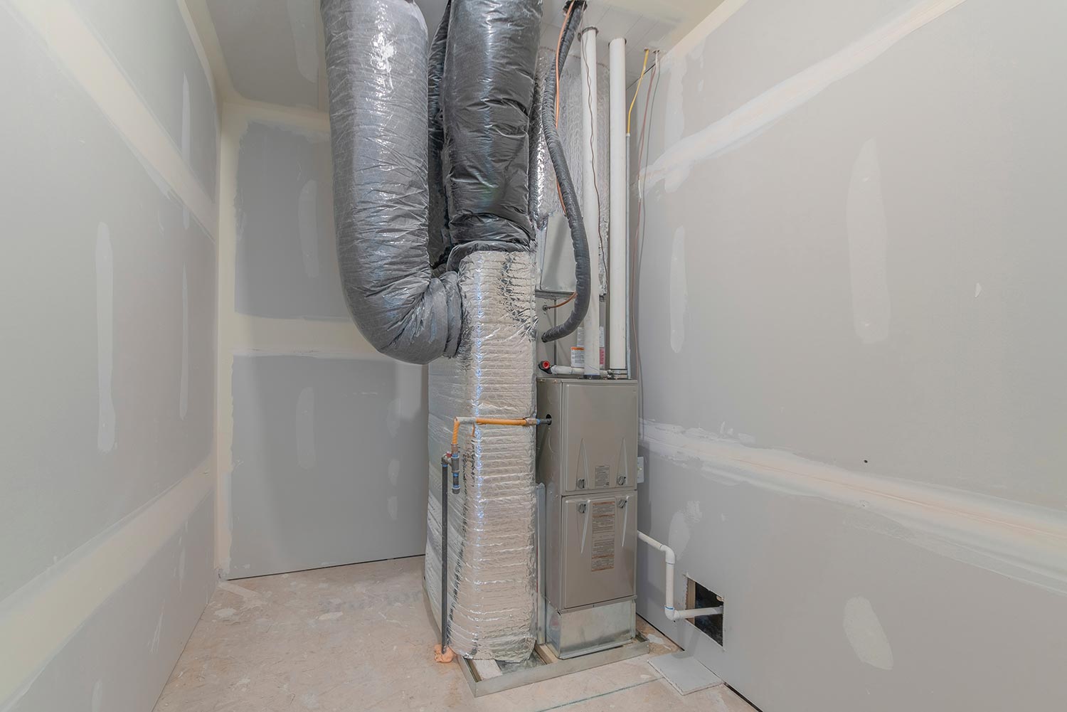HVAC system inside a utility closet room with white markings on the wall