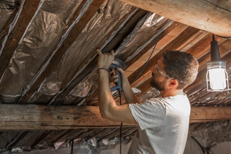 A man isolates the roofs of his house, How Long Does Radiant Barrier Insulation Last?