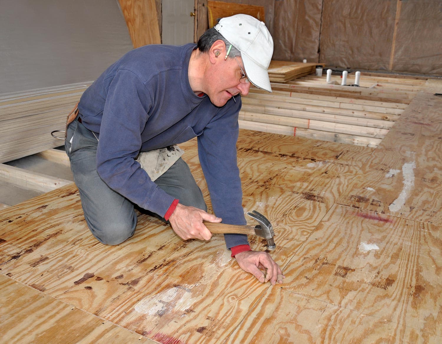 Man nailing down plywood sub-floor