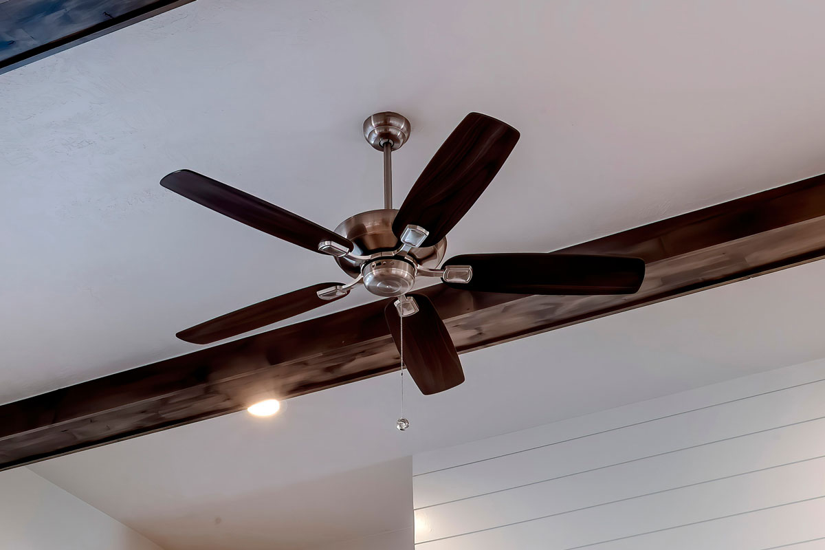 Square Ceiling fan with lights flanked by decorative wood beams and recessed lighting