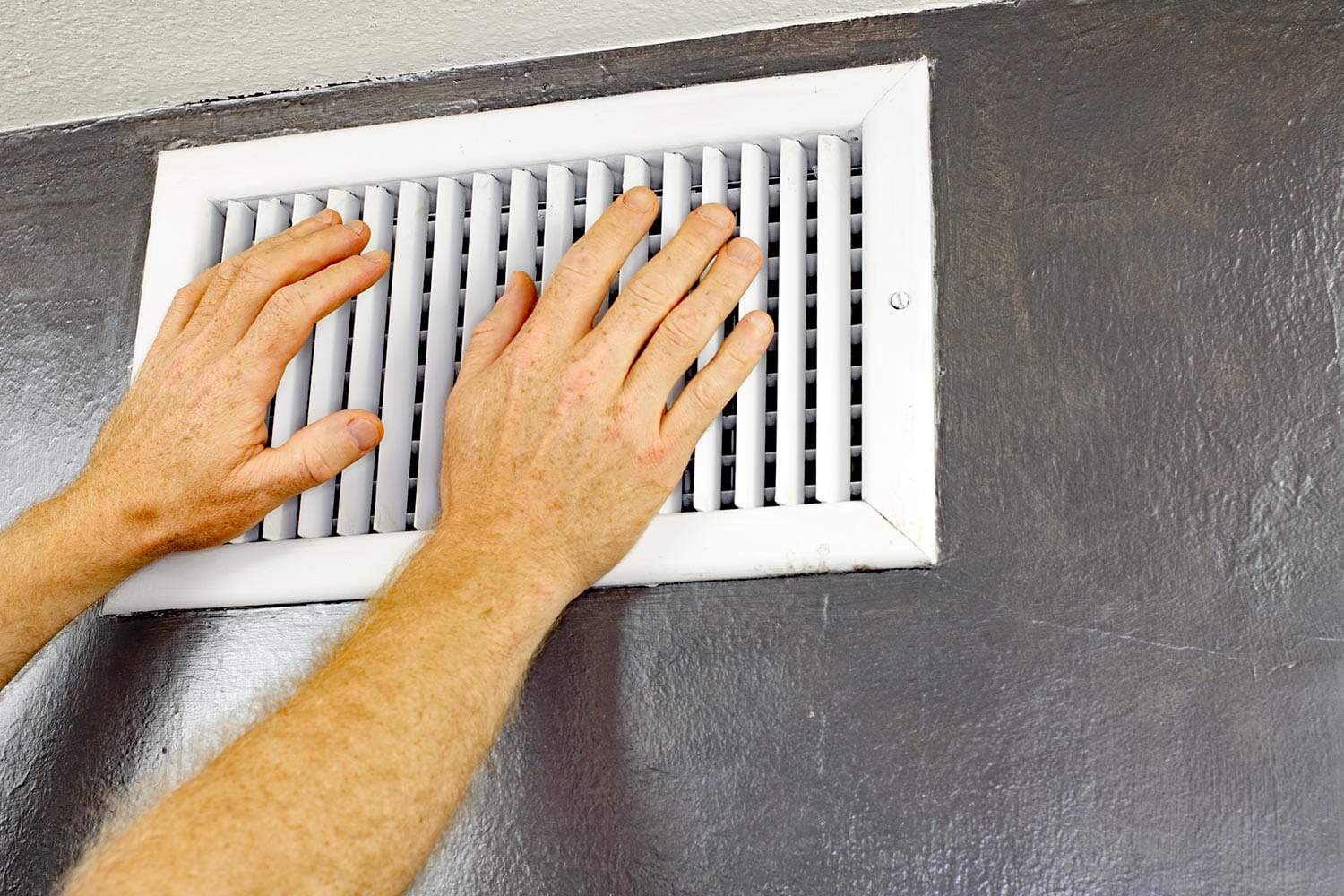 Two hands in front of an air vent