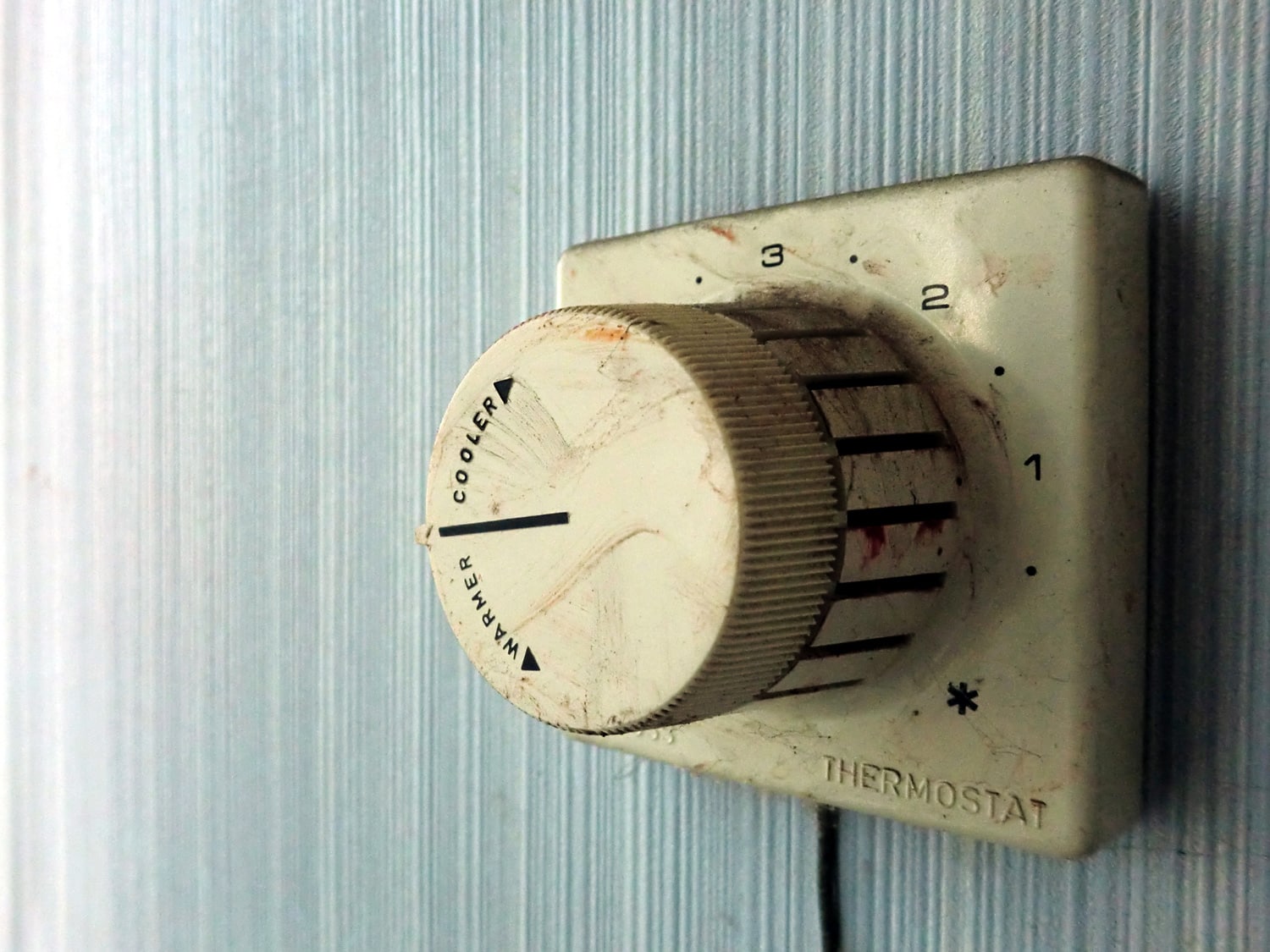 Vintage old grimy thermostat control on wall macro