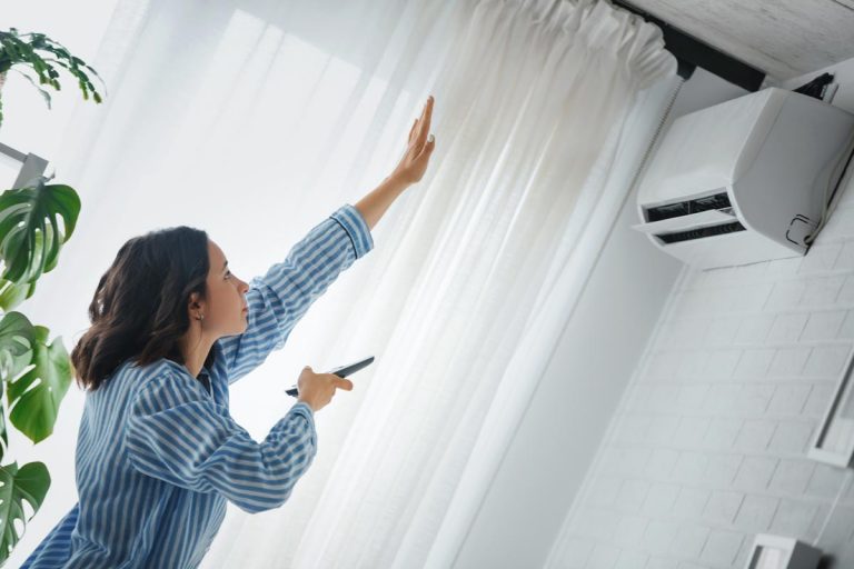 A woman is checking to see if the fan of the air conditioner is working, Rheem Air Conditioner Fan Not Working - What To Do?