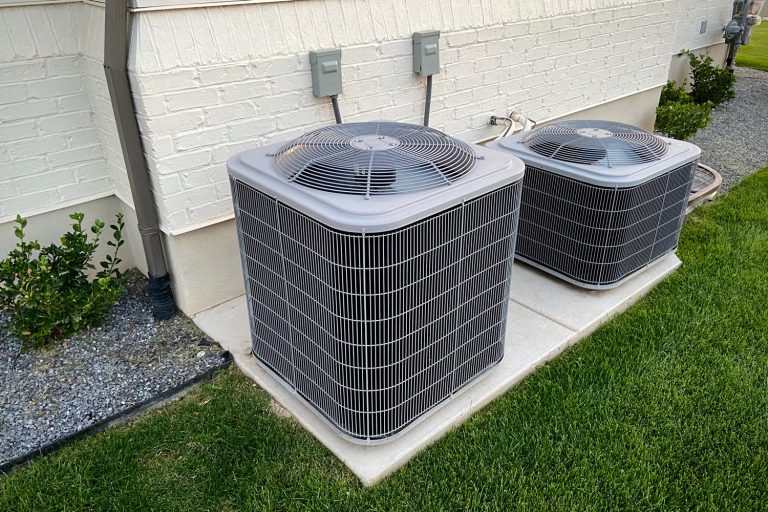 A big and small air conditioning unit mounted on small concrete slabs on the back of the house, How To Find Seer Rating On A Trane AC Unit