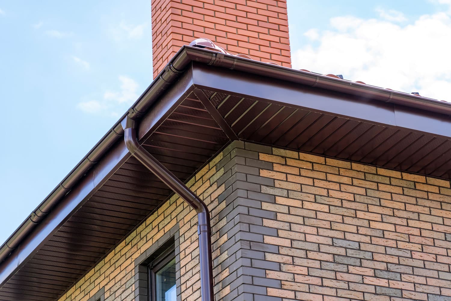 A brown painted soffit board with a downspout
