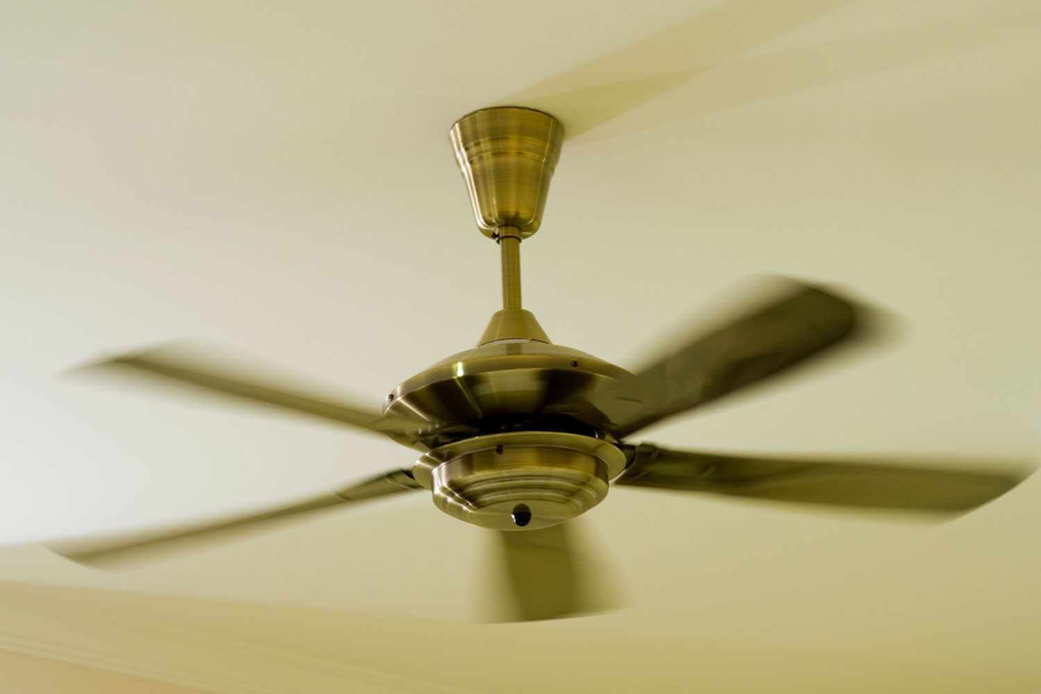 A ceiling fan spinning fast inside a room